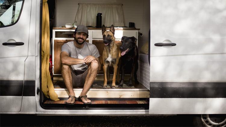 Smiling man sitting with his dogs in a motorhome