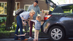 A family unloads groceries from the back of their SUV.